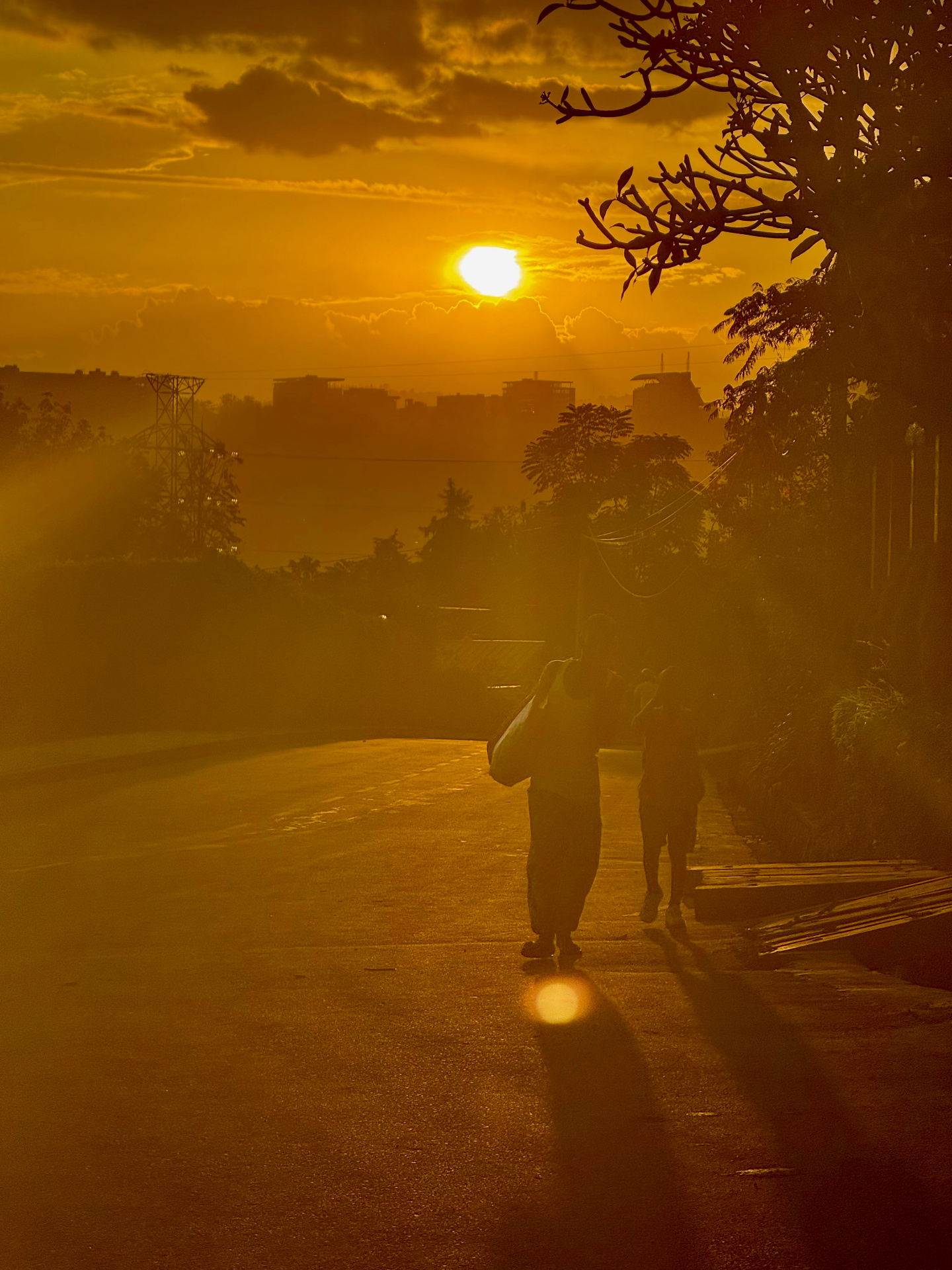Golden sunrise over Kigali, two figures walking down a misty road